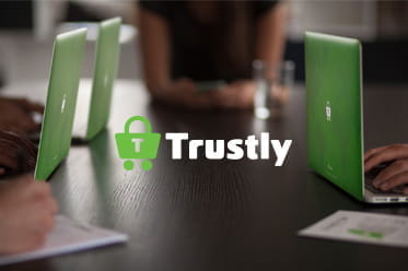 Het Trustly-logo en mensen die op laptops werken