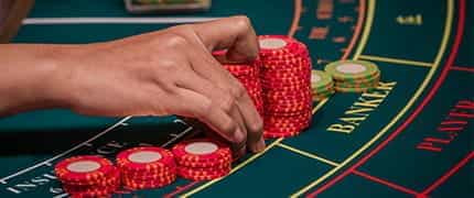 A player placing casino chips on a table as a wager for a hand of blackjack.