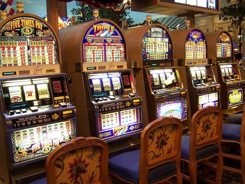 A row of brightly lit slot machines in a casino.