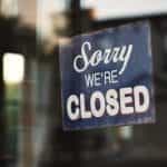 A shop window with a sign hung reading Sorry, We’re Closed.