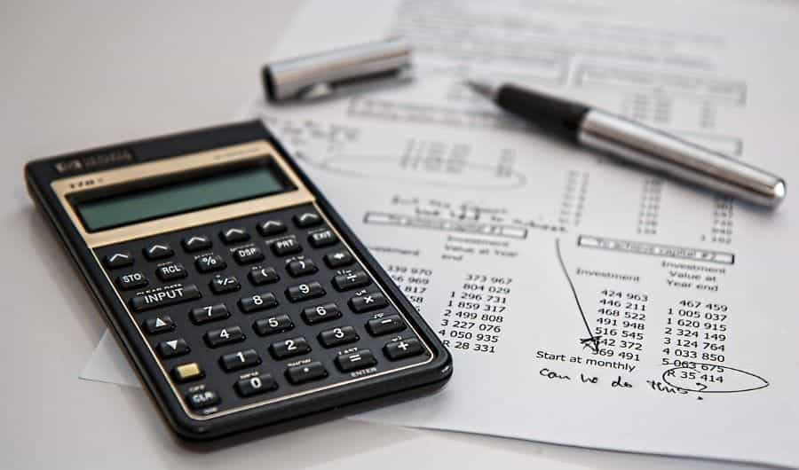 A calculator on a piece of paper with a pen next to it.
