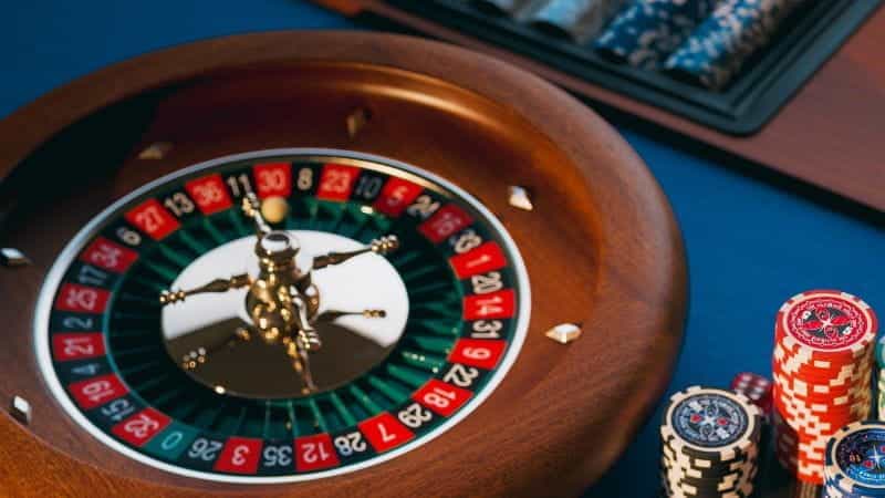 A classic roulette table at a casino with a stack of chips to the side.