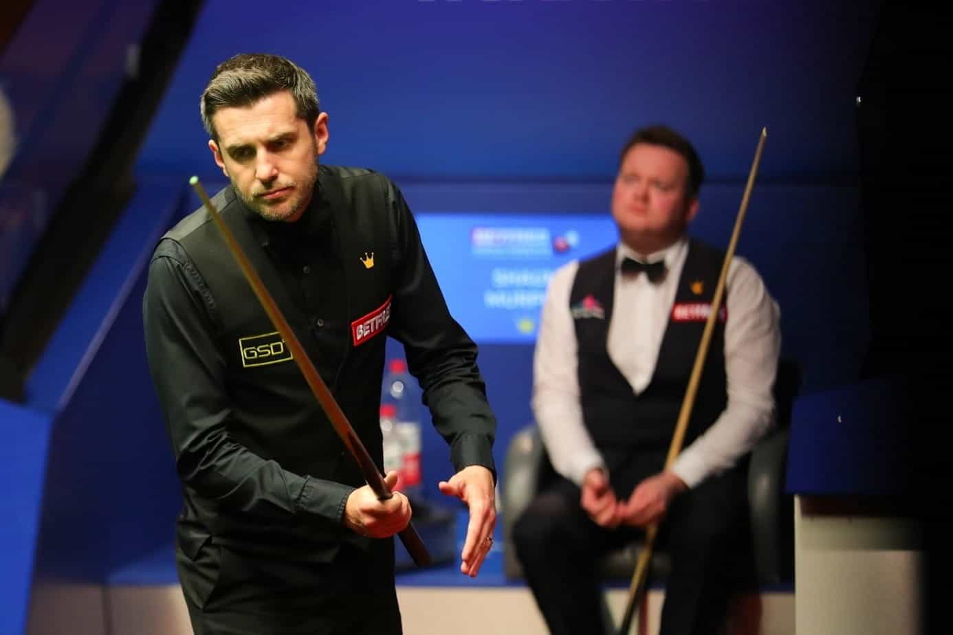 Mark Selby approaches a snooker table to play.