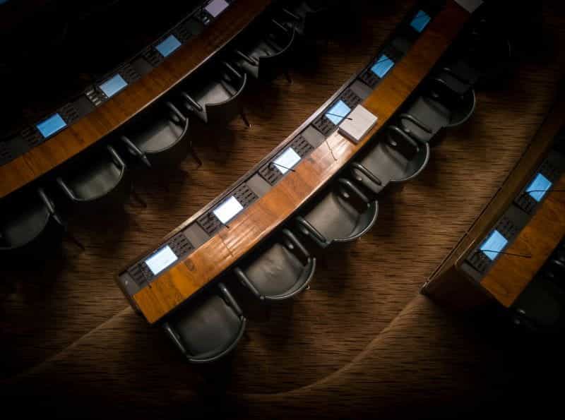 A top-down view of empty chairs in a parliamentary chamber.