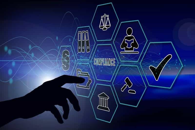 A finger pointing at a screen with images and words with Compliance at the centre.