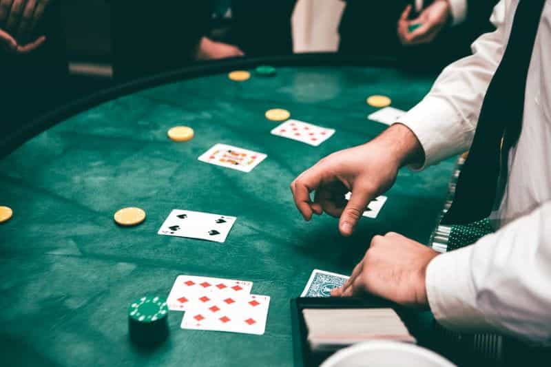 A croupier, dealing cards and chips at a poker table.