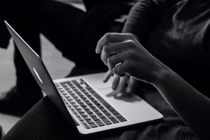 A black and white closeup of someone using a laptop.