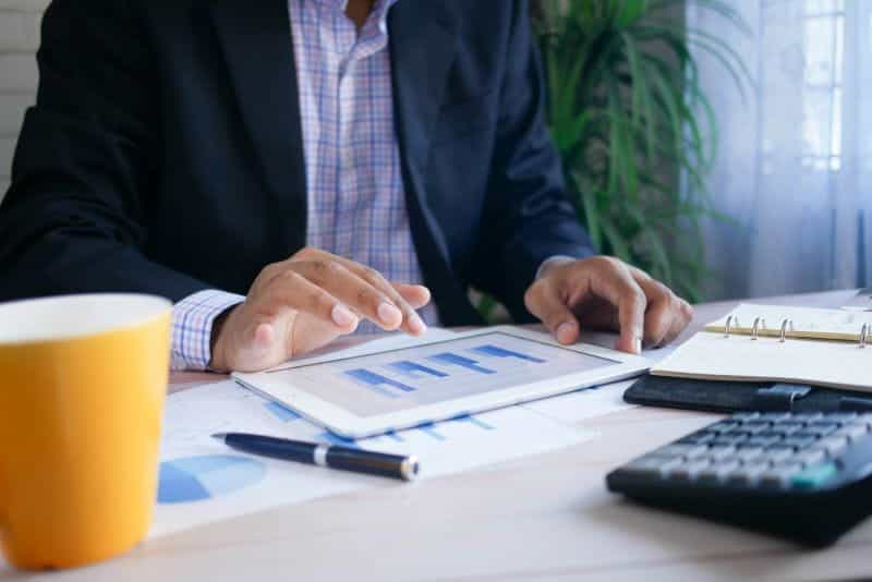 A person in a suit crunches numbers at a desk with a financial report in front of them.