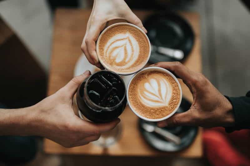 Three people clinking their coffee cups together.