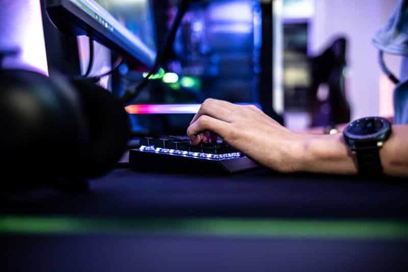 A man typing on a backlit keyboard.