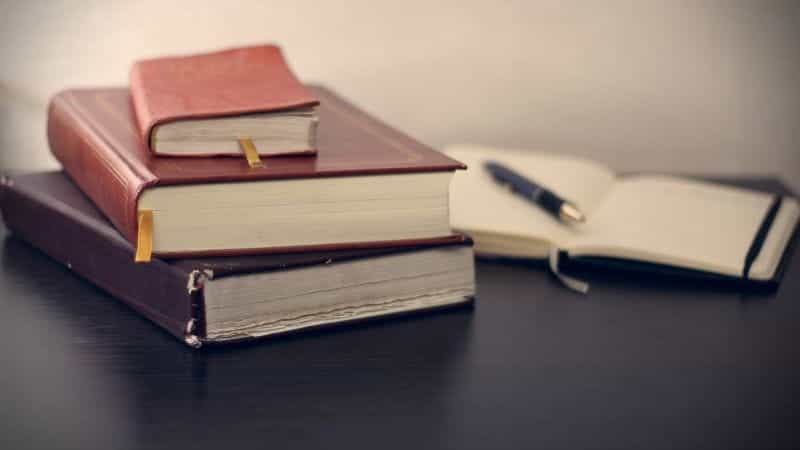 Several thick books with leather covers lay on a flat surface.