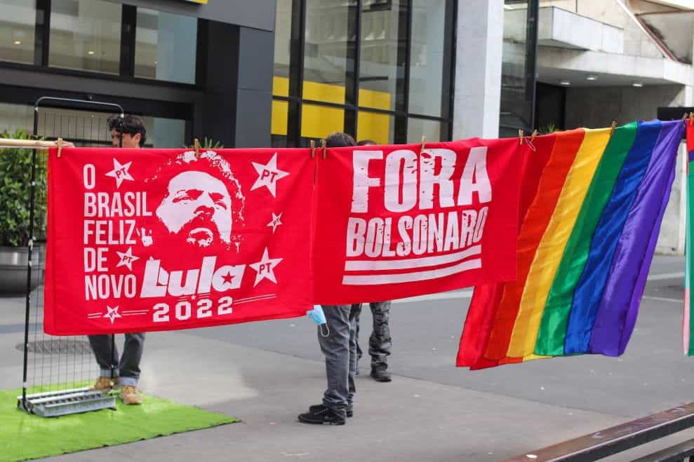 Two red flags feature Lula and "Fora Bolsonaro" next to a rainbow flag.