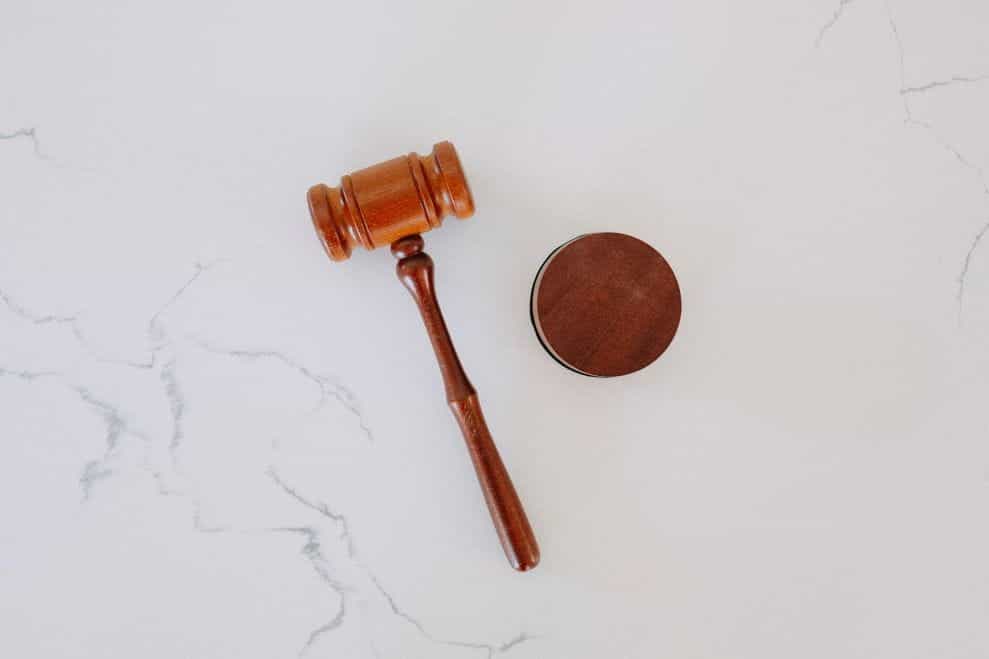 A wooden gavel sits on a marble surface.
