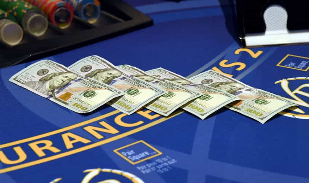 Five $100 bills placed on a blackjack table.