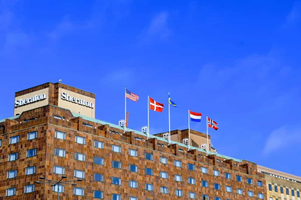 The front of a Sheraton building with flags of USA, Denmark, Sweden, Netherlands and Norway on the roof.