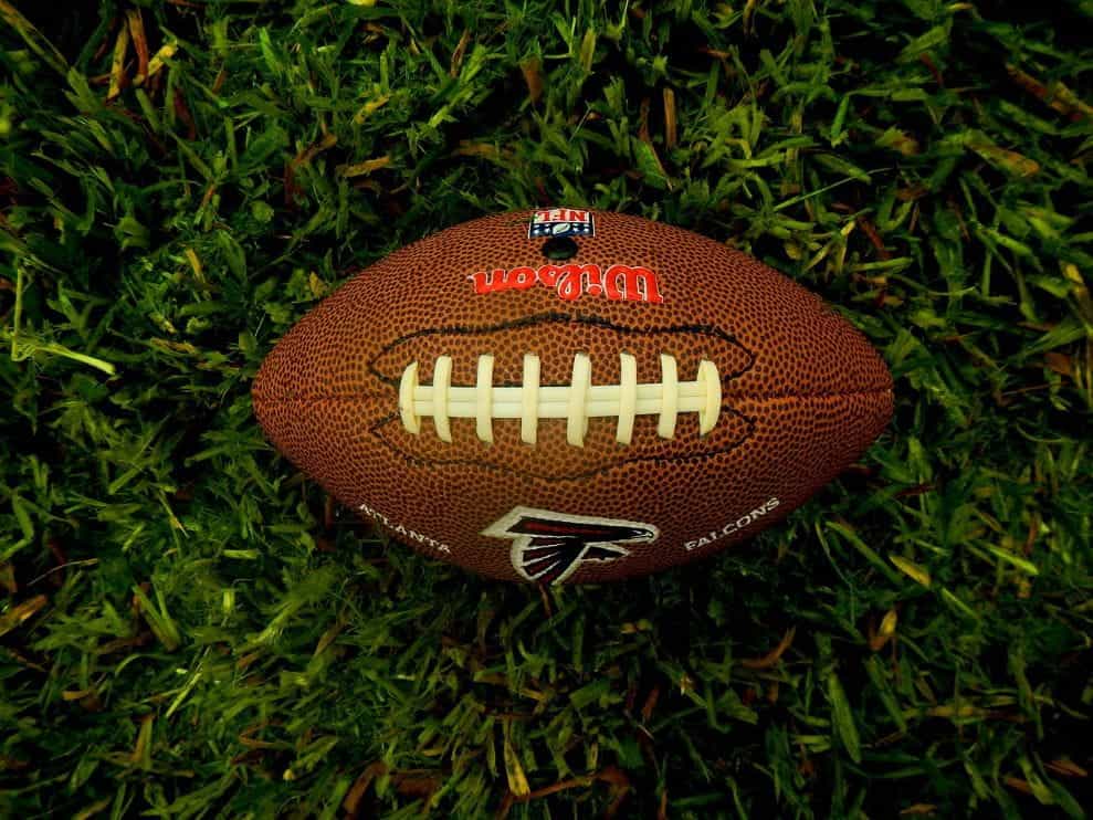 A classic American football laying horizontally on the grass of a football field.