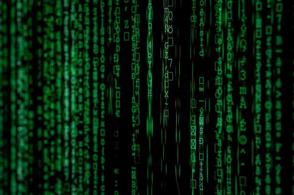 Strings of computer code in green light of a black screen.