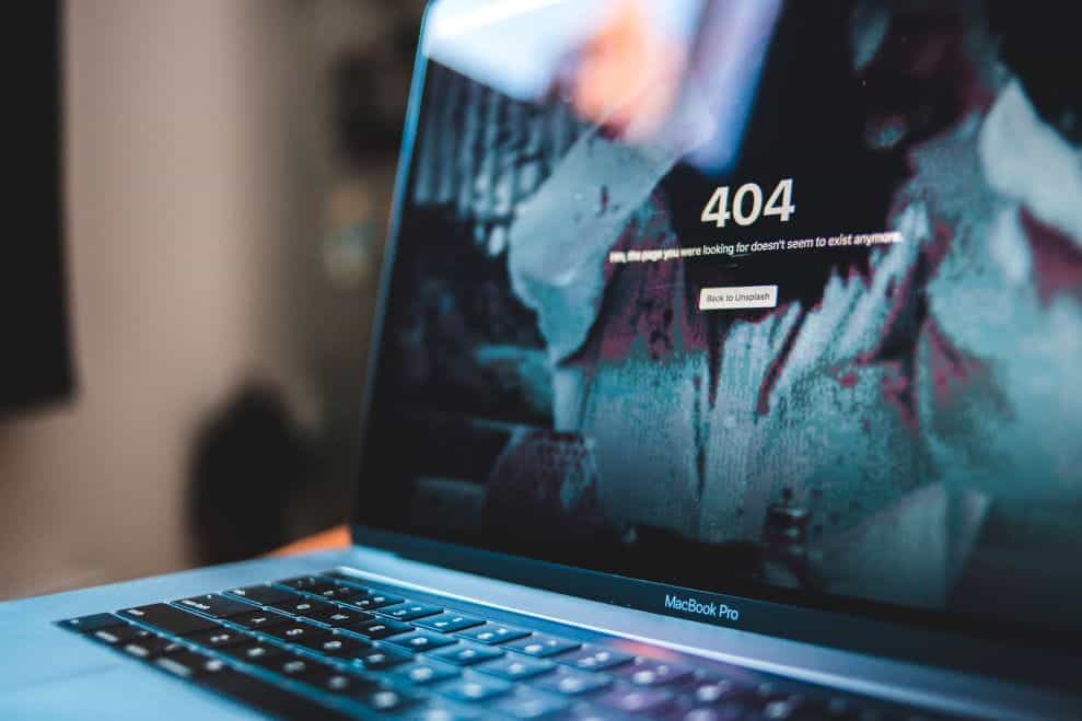 A 404 error shown on the browser of a silver and black laptop.