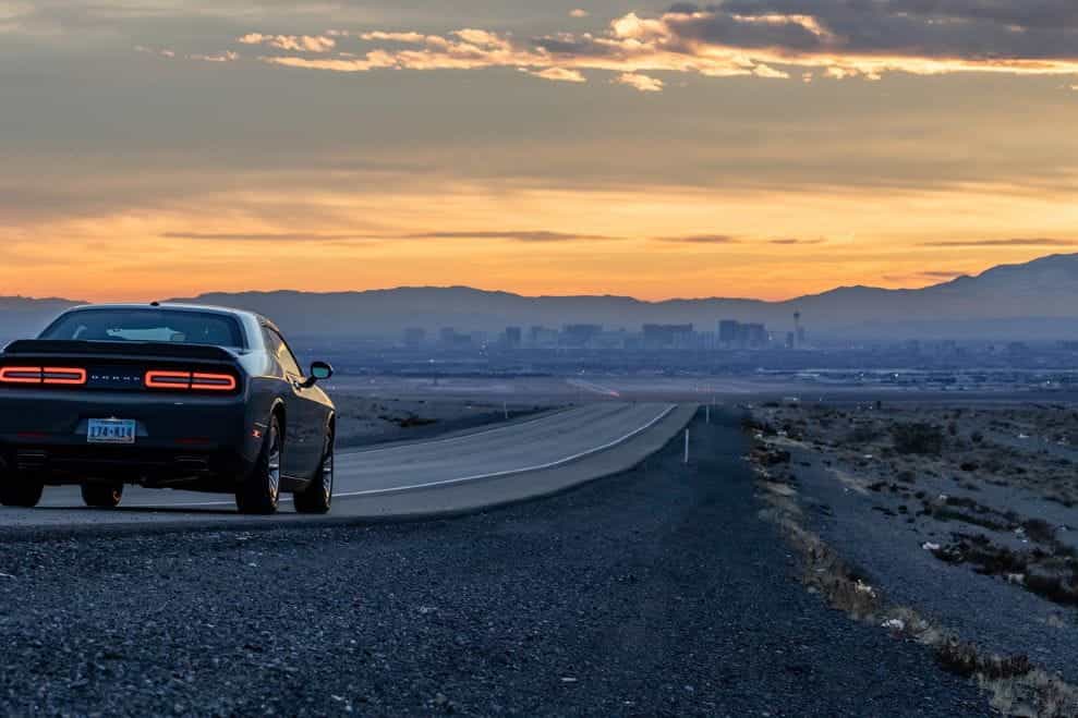 A black Ford Mustang driving down an empty road in the Nevada desert.