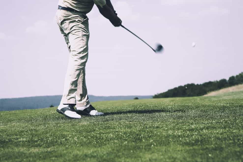 A person hitting a golf ball with a club on a golf course.