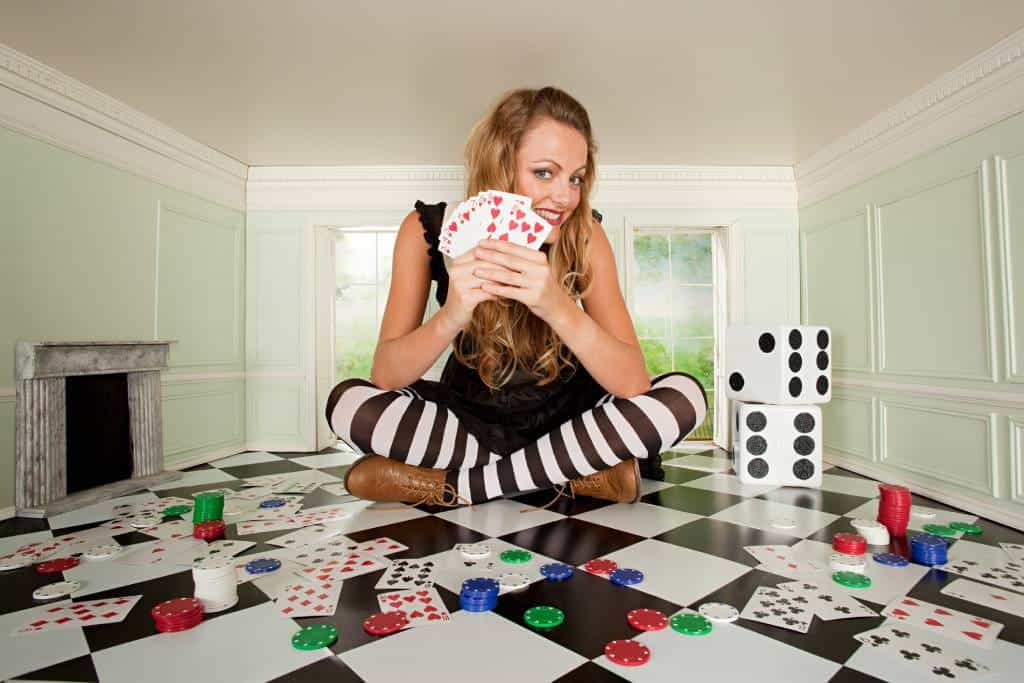 A young woman in small room with playing cards and dice.