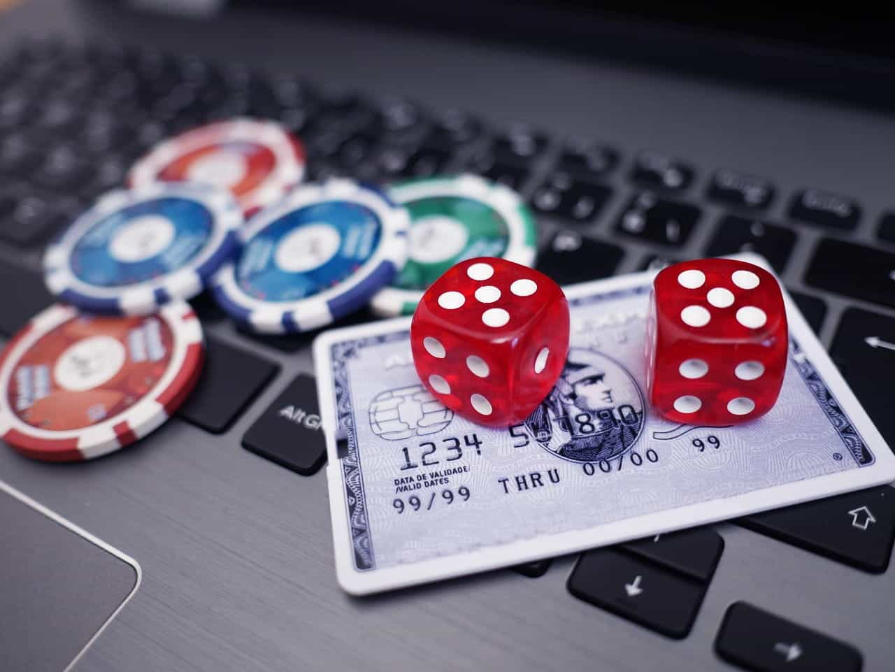 Several gambling chips, a pair of die and a credit card lying on top of a laptop computer’s keyboard.
