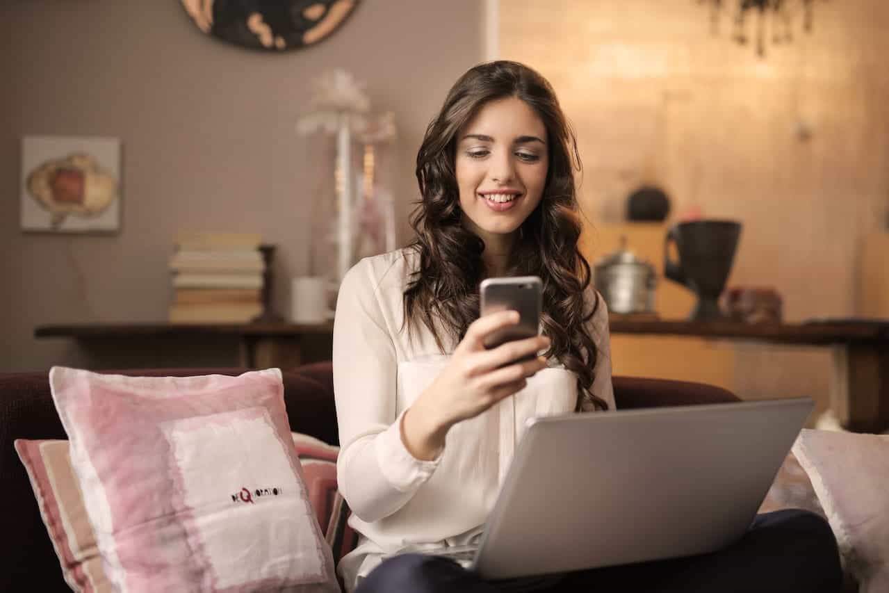 A woman using a laptop and a mobile phone.