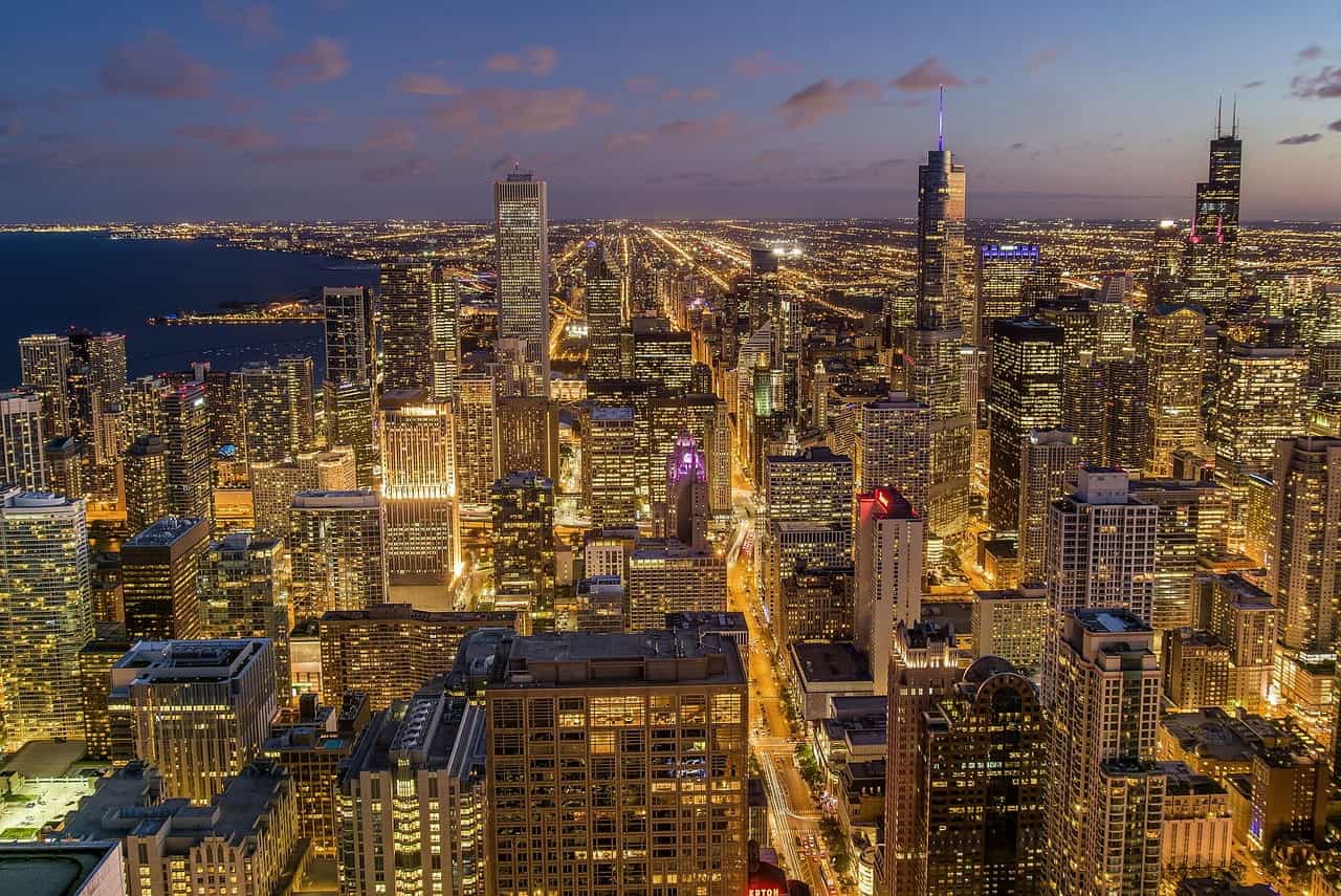 The dense and skyscraper-filled downtown area of Chicago, Illinois, with the sprawling city extending far out into the distance, flanked by Lake Michigan to the left.