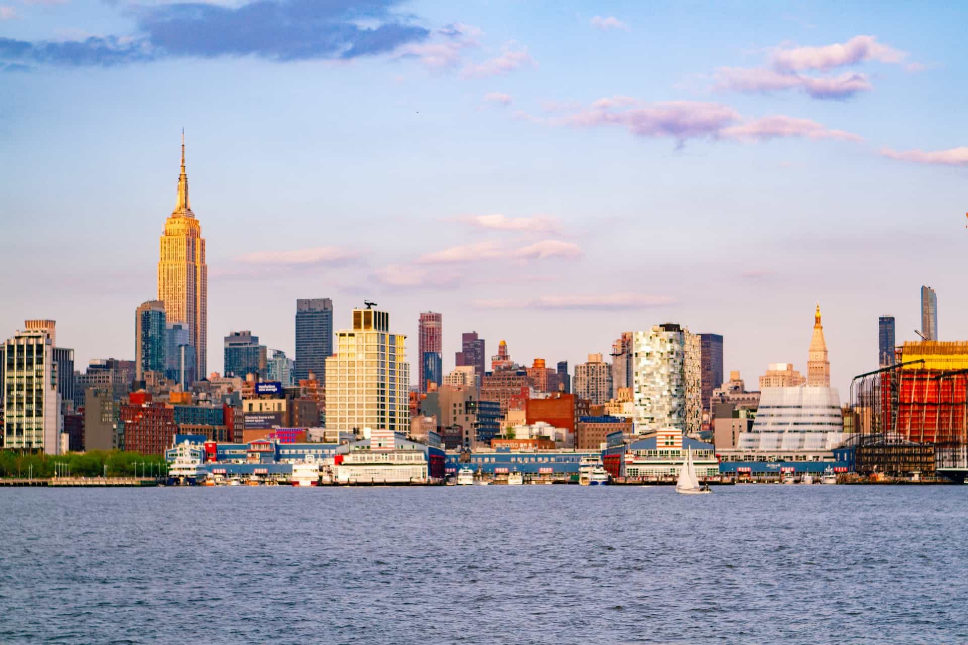 The skyline of a city in New Jersey as seen from a boardwalk of Manhattan in New York City, New York, featuring several skyscrapers and tall buildings and towers.