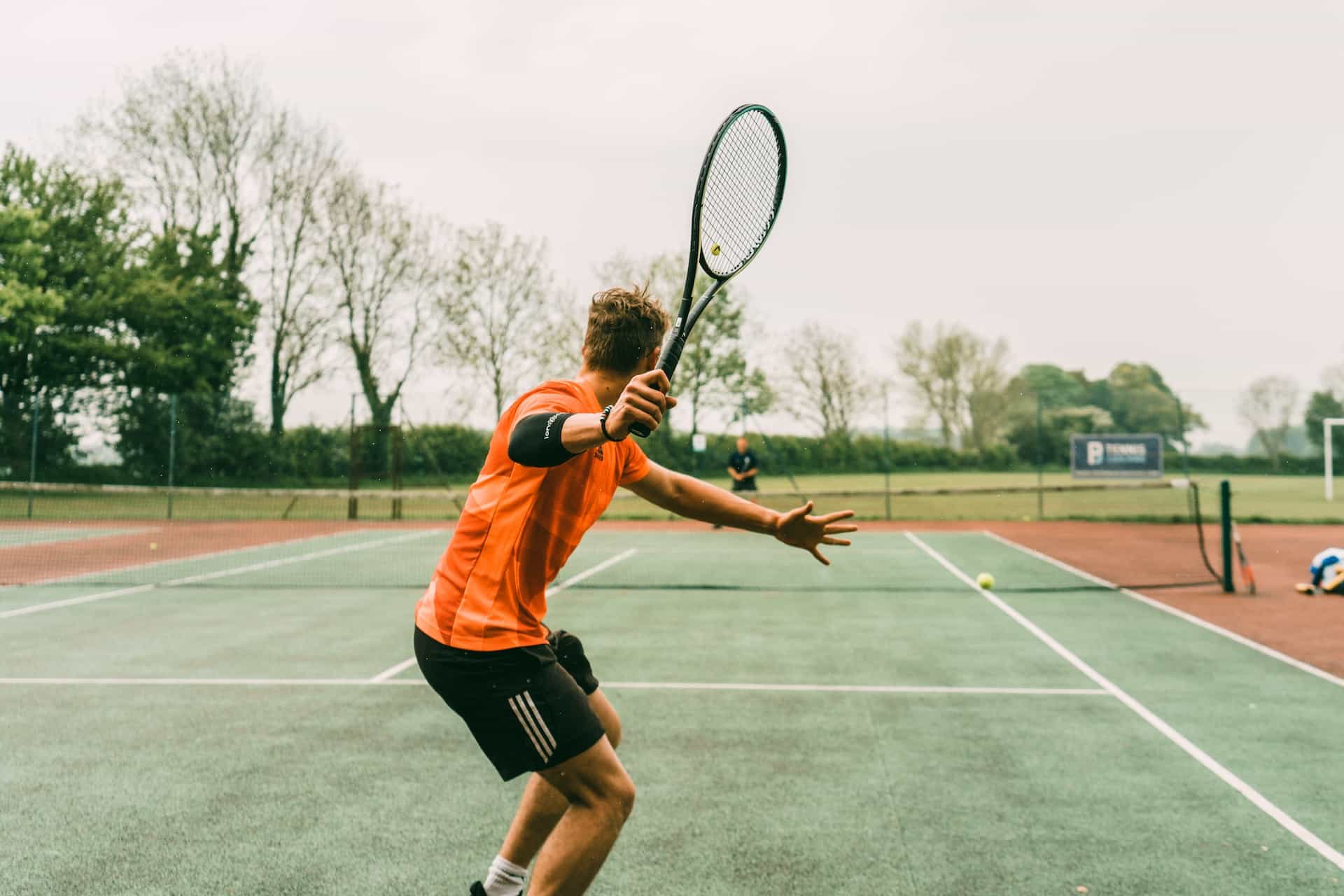 A male tennis player gets ready to swing his racket.