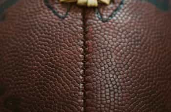 A very close up shot of an American football, featuring its iconic ridge and pigskin brown texture.