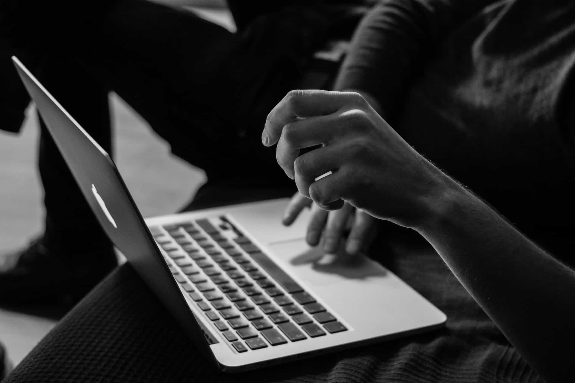 Hands type on a laptop keyboard.