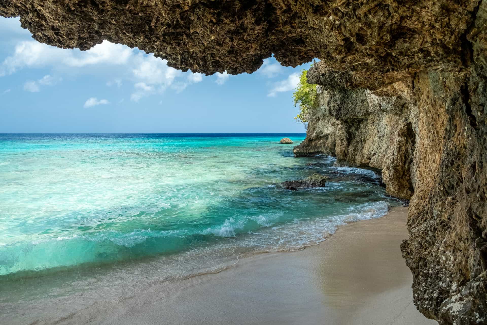 Bright blue ocean through a beachside cave.