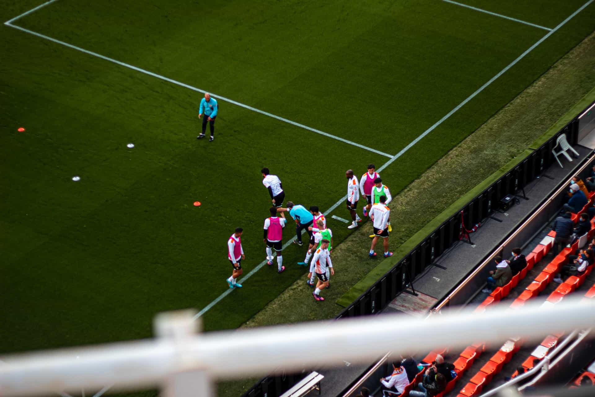 A group of soccer players in Spain stand just off the field in a stadium.