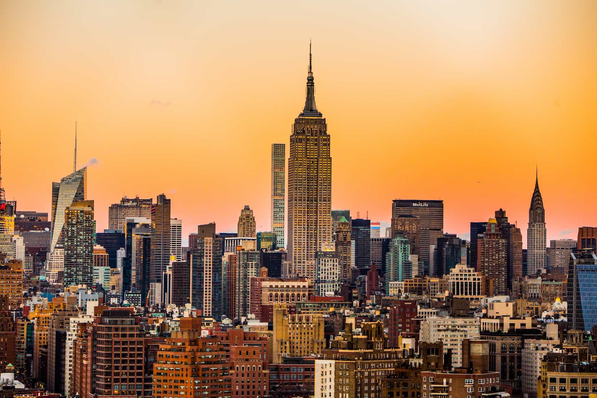 A dense collection of numerous tall buildings and skyscrapers on the island of Manhattan in New York City, New York, featuring the iconic Empire State Building in the center.