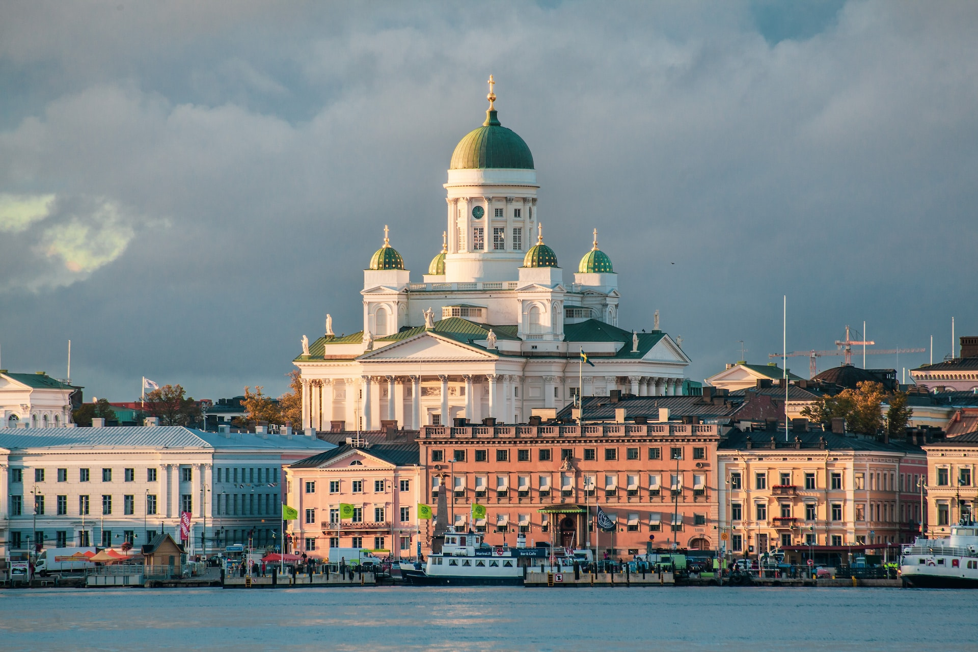 A white concrete cathedral rising behind buildings and a body of water.